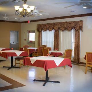 A spacious dining area featuring tables with red tablecloths and elegant curtains.
