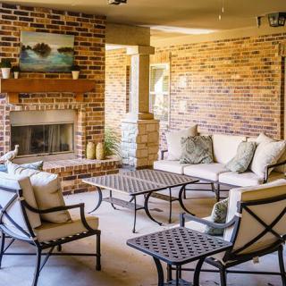 A cozy outdoor patio with comfortable seating and a brick fireplace.
