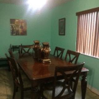 A cozy dining room with a wooden table and chairs, decorated with vases and artwork on the walls.