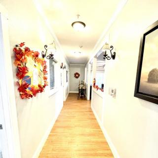 A brightly lit hallway with wooden flooring and decorative wreaths on the walls.