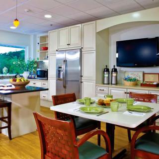A modern kitchen and dining area featuring sleek appliances, a large refrigerator, and a neatly set dining table.