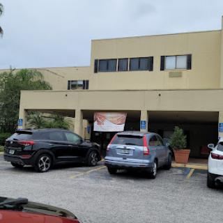 An exterior view of a building with several cars parked in front.