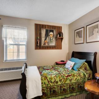 Cozy bedroom with single bed, colorful bedding, and artwork on the walls.