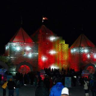 A vibrant ice structure illuminated with colorful lights during a night festival.