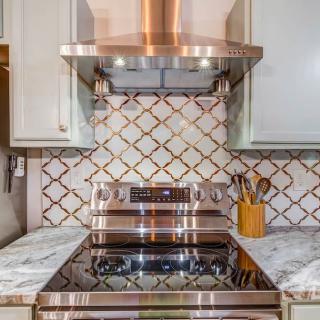 Modern kitchen with a stylish stove, intricate backsplash, and sleek range hood.