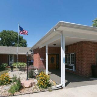 A brick building entrance with an American flag flying on a clear day.
