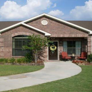 A single-story brick house with a front yard and a curved concrete pathway.