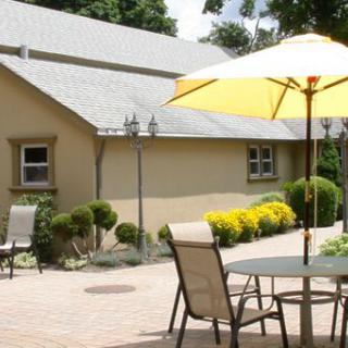 A sunny patio area with outdoor furniture and a yellow umbrella next to a garden.