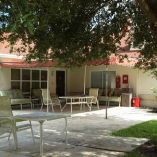 A peaceful outdoor patio area with tables and chairs under the shade of a large tree.