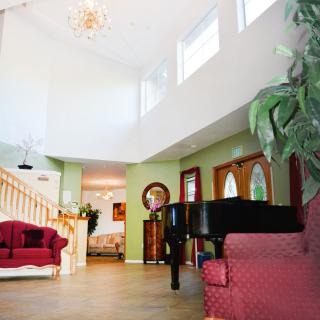 A spacious living room with a grand piano, elegant furniture, and a staircase leading to an upper level.