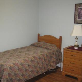 A small bedroom with a single bed and wooden furniture.