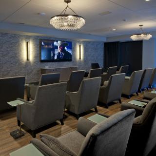 A modern home theater room with comfortable seating and a large TV screen.