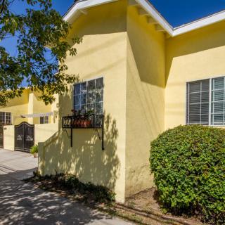 A bright yellow residential building with windows and surrounding greenery on a sunny day.