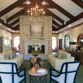 A beautifully designed living room featuring a stone fireplace and vaulted ceiling with wooden beams.
