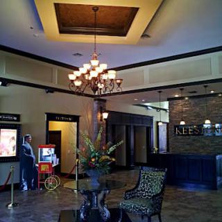 A hotel lobby featuring a chandelier, seating area, and reception desk with a popcorn machine in the corner.