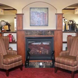 A cozy living room with a traditional fireplace flanked by two striped armchairs.