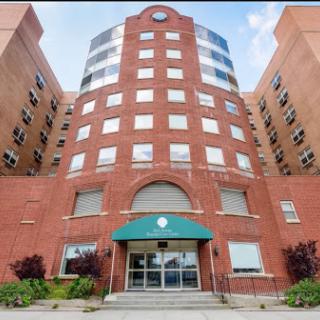 A modern brick building featuring a curved entrance and large windows.
