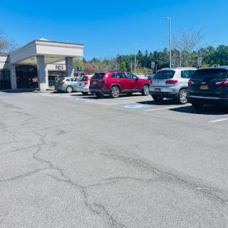 A sunny day at a parking lot with various vehicles parked outside a commercial building.