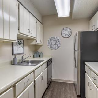 A modern kitchen with white cabinets and stainless steel appliances in a compact layout.