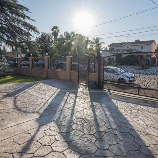 Driveway with long shadows cast by the gates in bright sunlight.