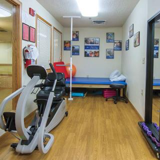 A small gym with exercise equipment and a large mirror on the wall.