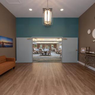 A modern lobby featuring a wooden floor, elegant chandelier, and contemporary decor.