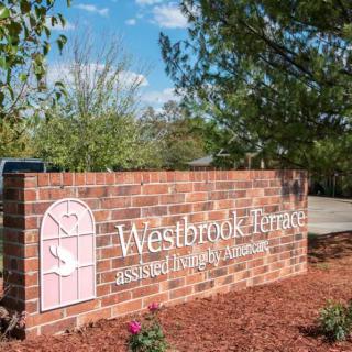 A brick sign for Westbrook Acres Assisted Living & Memory Care surrounded by a landscaped garden.