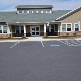 A view of the entrance to a modern building with a parking lot.