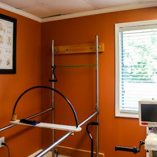 A well-equipped rehabilitation room featuring exercise apparatus against an orange wall, designed for fitness and therapy.