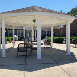 A sunny outdoor patio area featuring a gazebo with seating and tables.