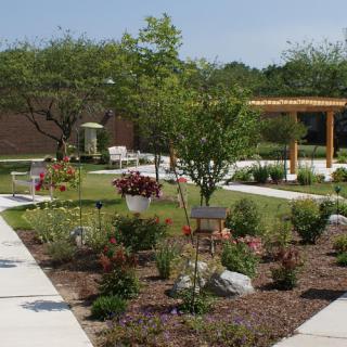 A serene outdoor garden space featuring neatly arranged plants, pathways, and seating areas.