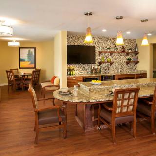 A modern kitchen with a bar counter and dining area featuring pendant lights and wood flooring.