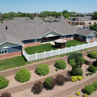 Aerial view of a well-maintained residential property featuring landscaped gardens and a fenced outdoor area.
