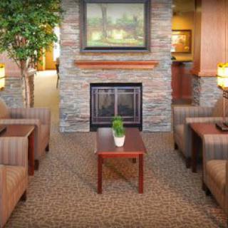 A cozy living room with a central fireplace, comfortable seating, and warm lighting.