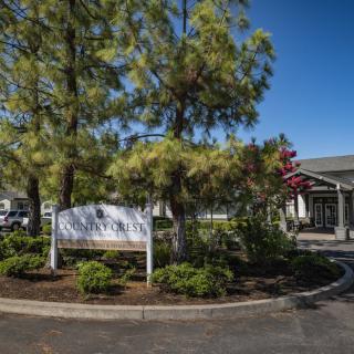 A building entrance surrounded by trees and landscaping under a clear blue sky.