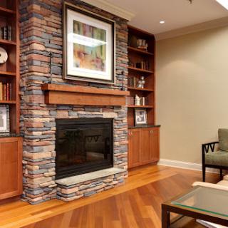 A stylish living room featuring a stone fireplace, wooden bookshelves, and contemporary furnishings.