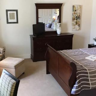 A well-decorated bedroom featuring a wooden bed, a matching dresser with a mirror, and an armchair.