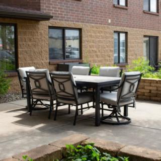 A cozy outdoor patio area with a table and chairs surrounded by plants.