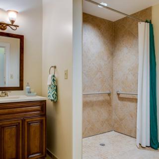 A bathroom featuring a sink with a mirror and an accessible walk-in shower.