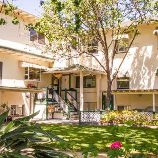 A residential apartment complex with a lush garden and trees.