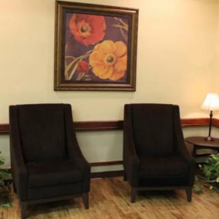 A cozy seating area with two chairs beneath a floral painting.