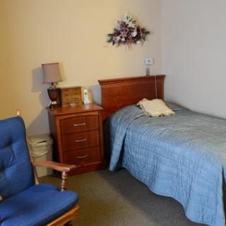 A cozy bedroom featuring a bed, dresser, and comfortable chair.