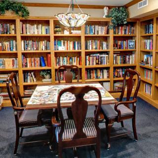 A cozy library with wooden bookshelves and a table with chairs in the center, perfect for reading and study.