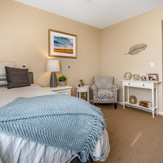 A cozy bedroom with a neatly made bed, a comfortable armchair, and stylish decor.