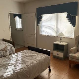 A cozy bedroom with two twin beds, a nightstand, and an armchair by the window.
