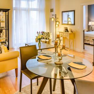 A modern living room with a glass dining table, cozy seating, and elegant decor.
