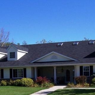 A suburban house with a well-maintained lawn under a clear blue sky.