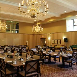 An elegant dining room with chandeliers, well-arranged tables, and chairs prepared for guests.
