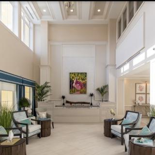 A modern and spacious lobby featuring comfortable seating, abundant natural light, and decorative plants.