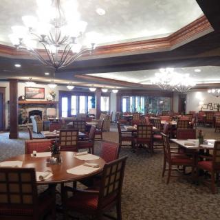 An elegant restaurant dining area with neatly arranged tables and chairs, illuminated by chandeliers.
